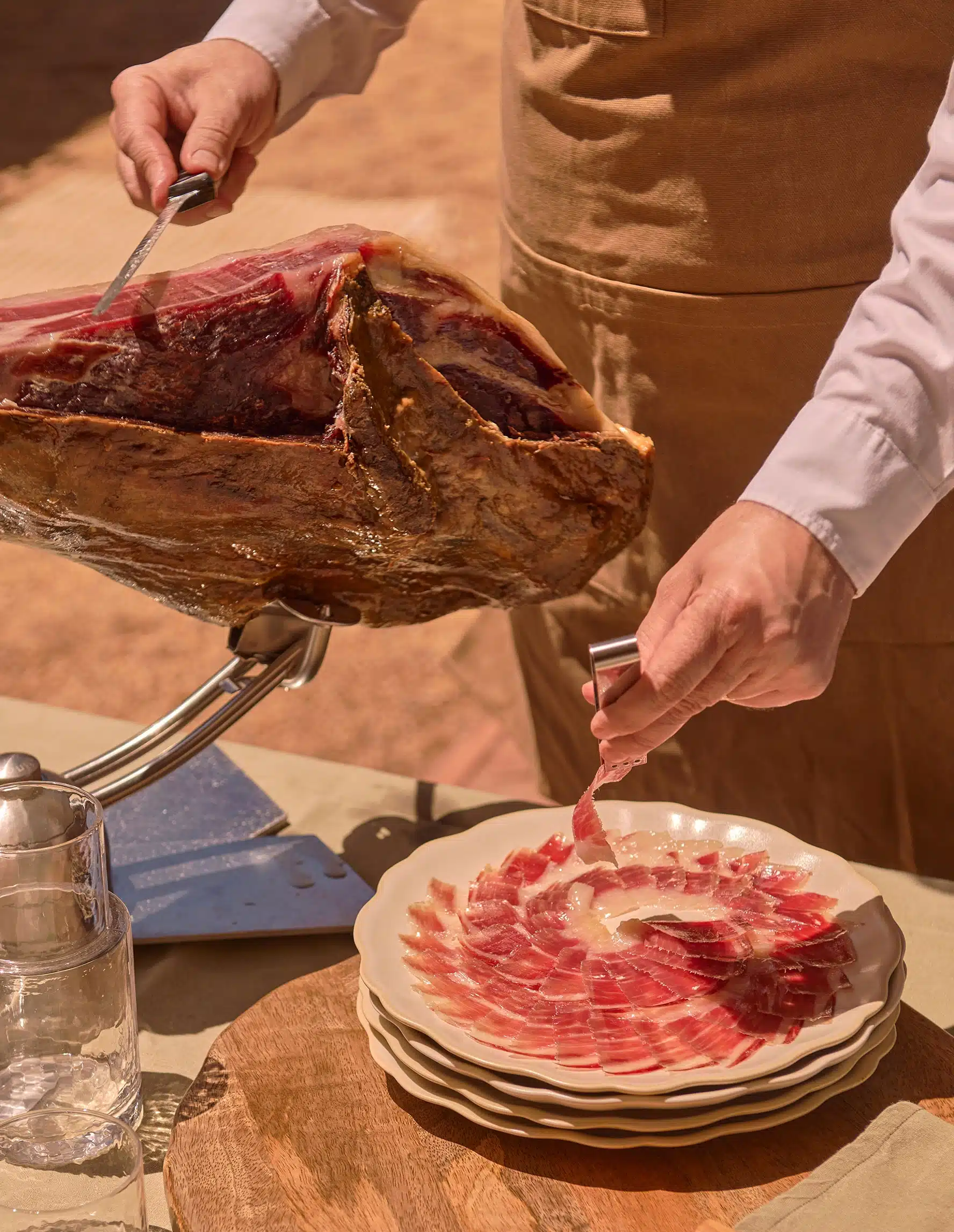 Detalle de cortador profesional sirviendo jamón ibérico en plato